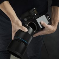 Valokuvaajan kädet pitelevät järjestelmäkameraa tekijänoikeuksista ja aineettoman omaisuuden oikeuksista kertovan oppaan kansikuvassa.