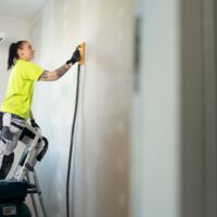 Nainen maalaamassa seinää.