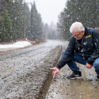 Taksiyrittäjä Timo Miettinen mittailee kädellään tien epätasaisuutta.