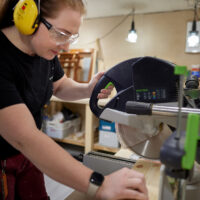 Henkilö sahaamassa puuta sirkkelillä.