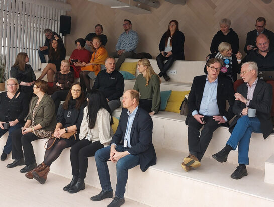 Ihmisiä katsomossa kuuntelemassa esitystä