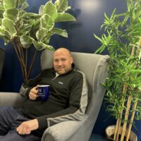 Alexander Ivaine istuu harmaassa nojatuolissa viherkasvien ympäröimänä