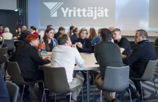 Ihmisiä tapahtumassa istumassa pöydän ympärillä