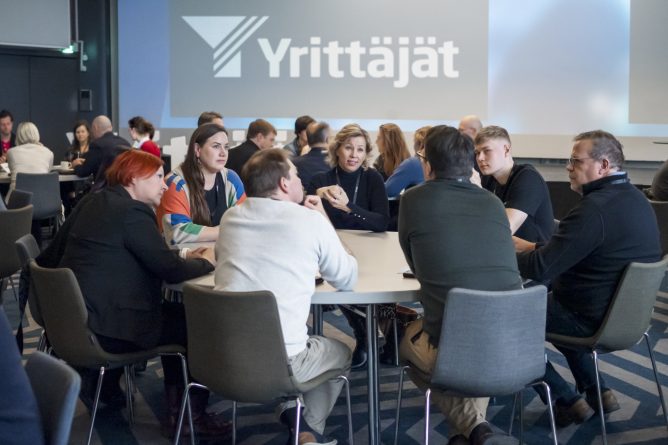 Ihmisiä tapahtumassa istumassa pöydän ympärillä