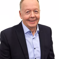 Hymyileväinen mies istuu ja katsoo kameraa.