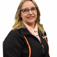 Nainen istuu ja katsoo kameraan ja hymyilee.