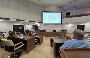 useita henkilöitä seuraa esitystä valtuustosalissa