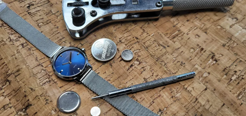 Rannekello ja paristoja puualustalla