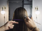 Brändikuvassa kampaaja leikkaa naisen pitkiä hiuksia.