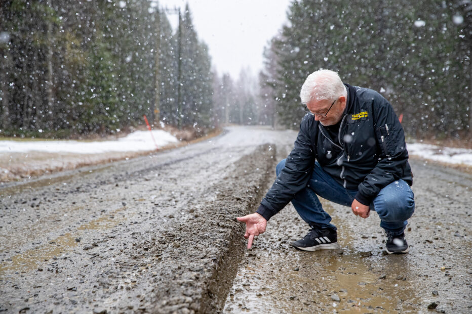 Taksiyrittäjä Timo Miettinen mittailee kädellään tien epätasaisuutta.